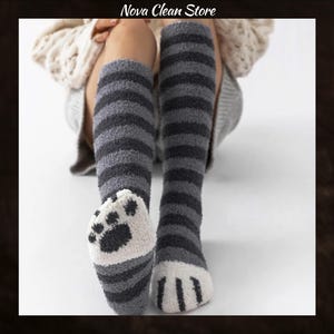 May include: Fluffy knee-high socks in grey and black stripes, featuring a cat paw design on the feet. These soft socks are ideal for relaxing. The image includes the text "Nova Clean Store" at the top.