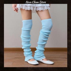 Peut inclure: Jambières bleu clair avec une texture côtelée. Les jambières sont portées avec des ballerines blanches. Le texte "Nova Clean Store" est visible en haut de l'image. Ces jambières sont un accessoire élégant.
