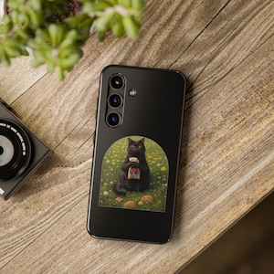 May include: A black smartphone case featuring a graphic of a black cat sitting in a field of yellow flowers, holding a Taco Bell bag with two tacos on the ground. The case has a vertical camera array with three lenses and a flash on the upper left side.