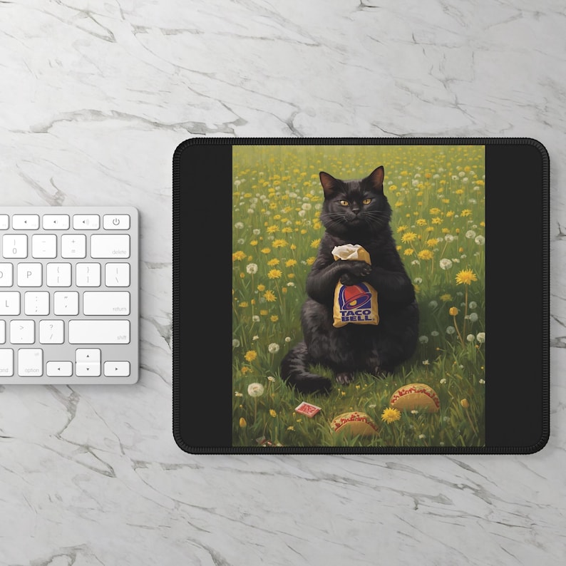 May include: A rectangular black mouse pad featuring a printed illustration of a black cat sitting in a field of yellow dandelions and white flowers. The cat is holding a Taco Bell paper bag, with two tacos resting on the grass in front of it.
