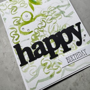 Peut inclure: Une carte de vœux blanche avec un fond de gribouillis aquarelle vert abstrait et de petits strass transparents. Le mot happy est écrit en grandes lettres noires découpées en gras, et le mot BIRTHDAY est imprimé sur une bannière blanche.