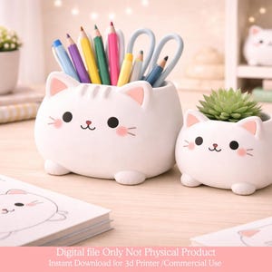 May include: Two white cat-shaped containers. One holds colorful pencils and scissors, the other a small succulent plant. Both have black eyes, pink cheeks, and small pink ears. The containers are on a light-colored surface.