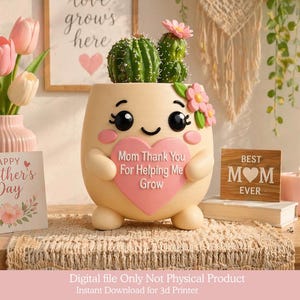 Puede incluir: Una maceta de cactus beige caprichosa con una cara sonriente y un corazón rosa que dice "Mom Thank You For Helping Me Grow". La maceta contiene un cactus verde. También hay una tarjeta de "Happy Mother's Day" y un letrero de "Best Mom Ever".