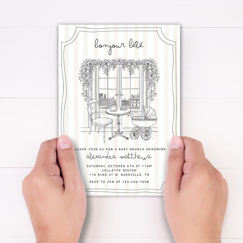 Puede incluir: Invitaci&oacute;n a un baby brunch en blanco y negro con el texto "bonjour b&eacute;b&eacute;". La invitaci&oacute;n presenta un dibujo lineal de una escena de caf&eacute; con una mesa, una silla y un cochecito. La invitaci&oacute;n est&aacute; sostenida por dos manos.