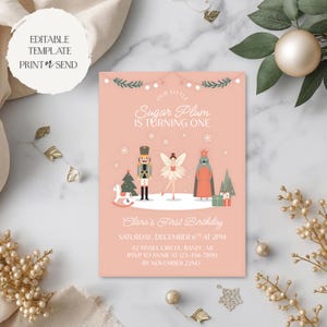 May include: A blush pink invitation with the text "Our Little Sugar Plum is Turning One." The invitation features illustrations of a nutcracker, fairy, and other festive elements. The text "Clara's First Birthday" is also included.