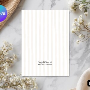 Puede incluir: Una tarjeta blanca con rayas verticales beige, el texto "registered at www.babylist.com" est&aacute; impreso en la parte inferior. La palabra "BACK" est&aacute; en un rect&aacute;ngulo negro. La tarjeta est&aacute; rodeada de flores blancas y una tela beige.