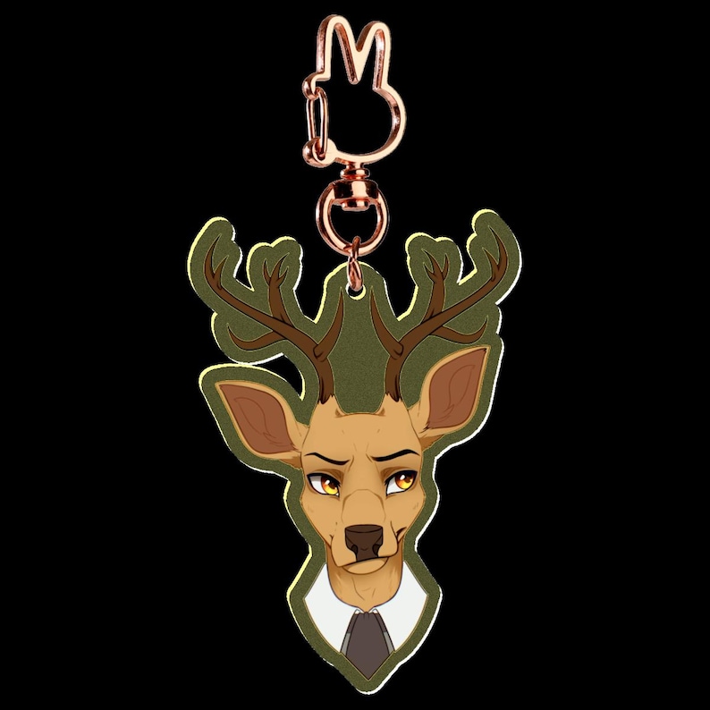 May include: A deer-shaped keychain with a copper-colored clasp. The deer has a tan face, brown antlers, and is wearing a white collared shirt and a dark tie. The background is black.