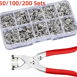 May include: A clear plastic organizer box filled with silver snap fasteners, labeled "50/100/200 Sets." Below, a silver and red snap fastener pliers tool is displayed, ready for use. The image showcases a set of tools for crafting and sewing projects.