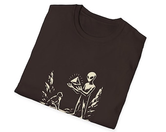 Camiseta con diseño gráfico de extraterrestre, ovni, espacio y pirámide levitando, con un ser humano primitivo alienígena sosteniendo una calavera de cristal.