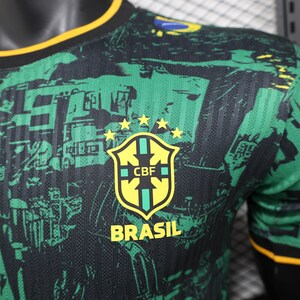 K&ouml;nnte beinhalten: Gr&uuml;nes und schwarzes Brasilien-Fu&szlig;balltrikot mit gelbem Kragen und &Auml;rmelbesatz. Das Trikot hat ein Schild mit den Buchstaben "CBF" und dem Wort "BRASIL" in Gelb. F&uuml;nf gelbe Sterne befinden sich &uuml;ber dem Schild. Das Trikot hat ein sich wiederholendes Muster architektonischer Elemente.