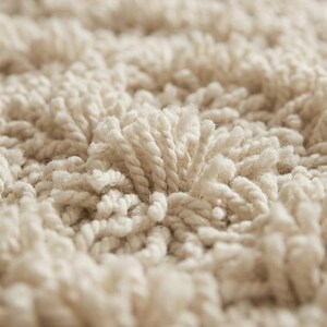 May include: A high-pile rug featuring a dense, textured surface made of off-white, twisted yarn loops. The material creates a thick, shaggy appearance with a consistent, monochromatic cream color throughout the entire visible area.