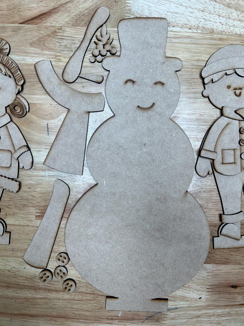 以下が含まれることがあります： クラフト用の、未完成の木製雪だるまと子供たちの切り抜き。雪だるまはシルクハット、笑顔の顔、別々の腕、ベリーの枝を持っています。子供たちは冬服を着ています。小さな木製のボタンが含まれています。