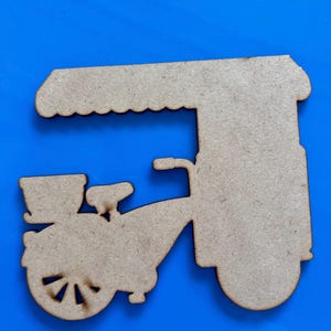 May include: A wooden cutout of a bicycle with a canopy, likely for crafting or decoration. The bicycle has a basket, seat, and a rounded wheel. The canopy has a scalloped edge. The cutout is made of light brown wood.