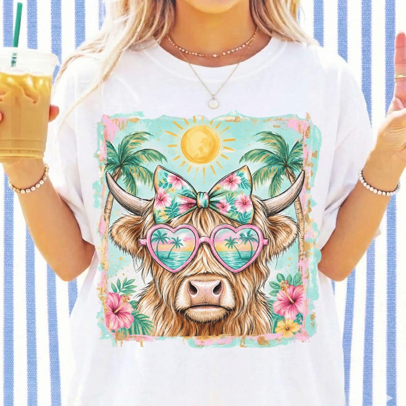 May include: A white t-shirt featuring a graphic of a highland cow wearing heart-shaped sunglasses with a tropical beach scene, a floral bow, palm trees, and a yellow sun. The design includes pink and yellow hibiscus flowers on a light blue background.