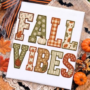 May include: A white rectangular sign featuring the text FALL VIBES in large, fabric-appliqued block letters. The letters are decorated with various patterns including floral prints, orange and white gingham, polka dots, and stripes.