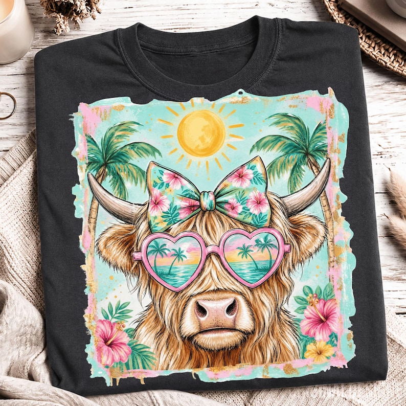 May include: A black t-shirt featuring a graphic of a Highland cow wearing heart-shaped sunglasses with a tropical beach reflection. The cow has a floral bow on its head, surrounded by palm trees, a yellow sun, and pink hibiscus flowers.