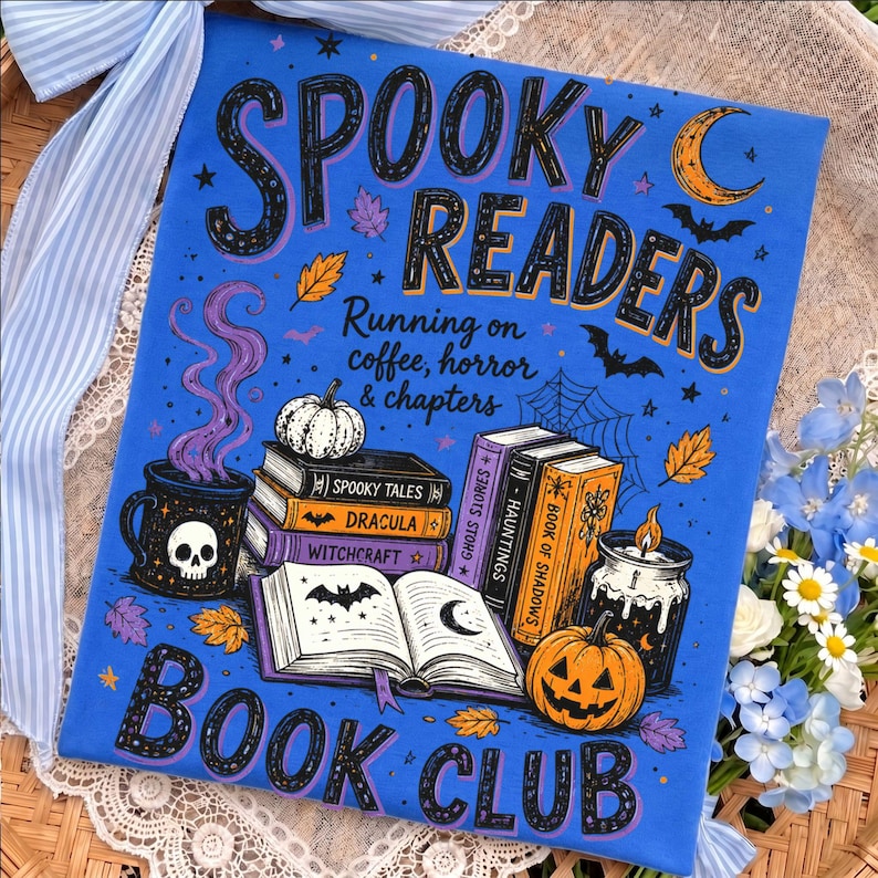 May include: A bright blue t-shirt featuring the text "SPOOKY READERS" and "BOOK CLUB" with "Running on coffee, horror & chapters". The graphic includes a skull mug, stacked books titled "Spooky Tales", "Dracula", "Witchcraft", "Hauntings", and "Book of Shadows", a jack-o'-lantern, a candle, bats, and autumn leaves.