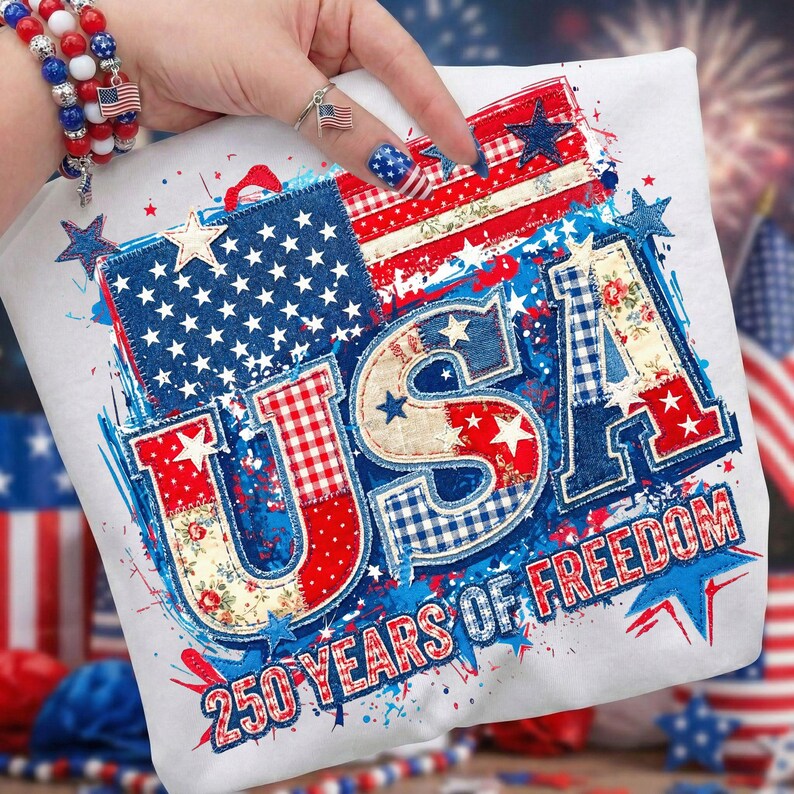May include: White t-shirt with a patriotic USA design. The design incorporates the American flag, stars, and the text "250 YEARS OF FREEDOM" in red, white, and blue. The shirt has a patchwork style.