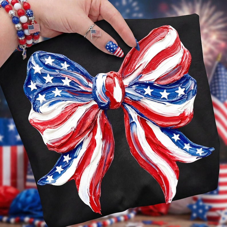 May include: A black pillow featuring a large, textured bow design in red, white, and blue, reminiscent of the American flag. The bow has white stars on a blue background. The pillow is a patriotic decorative item.