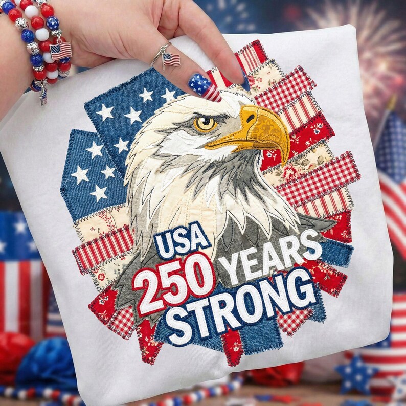 May include: White t-shirt featuring a detailed illustration of a bald eagle with the text "USA 250 YEARS STRONG." The design incorporates patriotic elements like stars and stripes, celebrating a milestone anniversary.