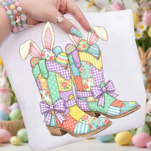 May include: A white square pillow featuring a colorful patchwork design of Easter-themed cowboy boots. The boots are filled with decorated Easter eggs and bunny ears. Each boot has a large purple bow. The pillow is held by a person.