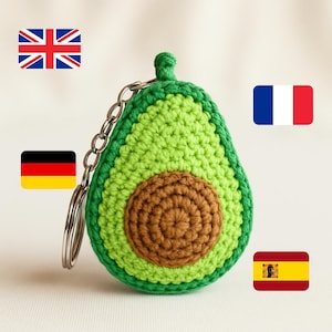 Może przedstawiać: Ręcznie robiony brelok w kształcie awokado. Brelok jest wykonany na szydełku z zielonej i brązowej przędzy, ze srebrnym łańcuszkiem i kółkiem na klucze. Awokado ma szczegółowe nasiono pośrodku i zieloną łodygę. Zabawny i unikalny dodatek.