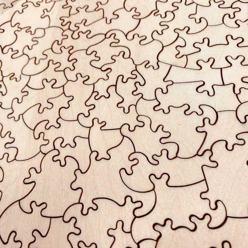 May include: A close-up of a wooden jigsaw puzzle with a natural wood finish. The puzzle pieces are cut in a unique, intricate design, creating a complex and challenging puzzle.