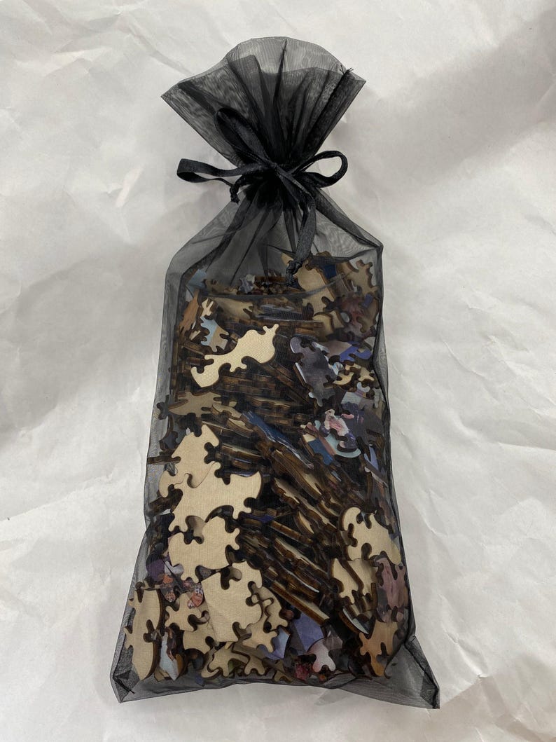 A black mesh bag filled with wooden puzzle pieces is shown against a white background.