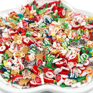 May include: A collection of colorful Christmas-themed resin embellishments in a white dish. The assortment includes Santa Claus, reindeer, gingerbread men, Christmas trees, and other festive shapes in red, green, white, and brown.