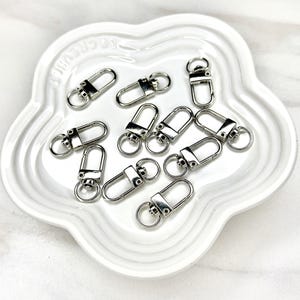Shiny silver and gold 12x33mm swivel lobster clasps for keychains, bag charms, jewelry making, and DIY craft supplies.