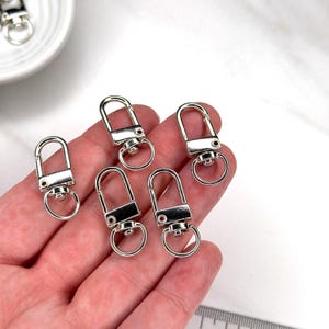Shiny silver and gold 12x33mm swivel lobster clasps for keychains, bag charms, jewelry making, and DIY craft supplies.