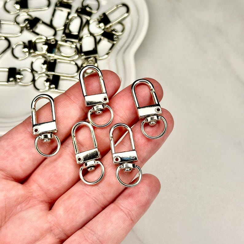 Shiny silver and gold 12x33mm swivel lobster clasps for keychains, bag charms, jewelry making, and DIY craft supplies.