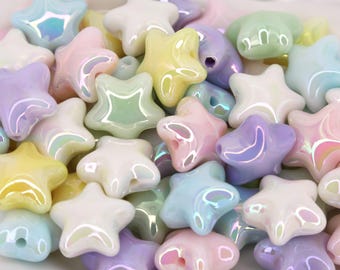 May include: A collection of pastel-colored star-shaped beads. The beads are in shades of pink, yellow, blue, green, and purple, with an iridescent sheen. Each bead has a hole for stringing. The beads are likely for jewelry making or crafts.