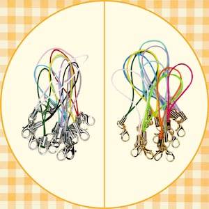 May include: Two sets of colorful lanyards with lobster claw clasps. One set features silver-toned clasps and a variety of cord colors, including red, green, and yellow. The other set has gold-toned clasps and a different array of cord colors.