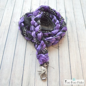 May include: Purple and black braided dog leash with rhinestones and a silver clip.  Foo Foo Fido.