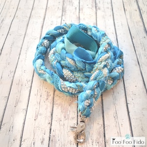 May include: A blue and silver braided dog leash with a silver clip. The leash is made of fabric and has a sparkly design.