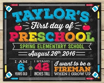 May include: A chalkboard-style sign with the text "Taylor's First day of Preschool." It includes the date August 26th, 2016, and the child's age, height (42 inches), and future aspiration to be a fireman. The sign is decorated with colorful accents.