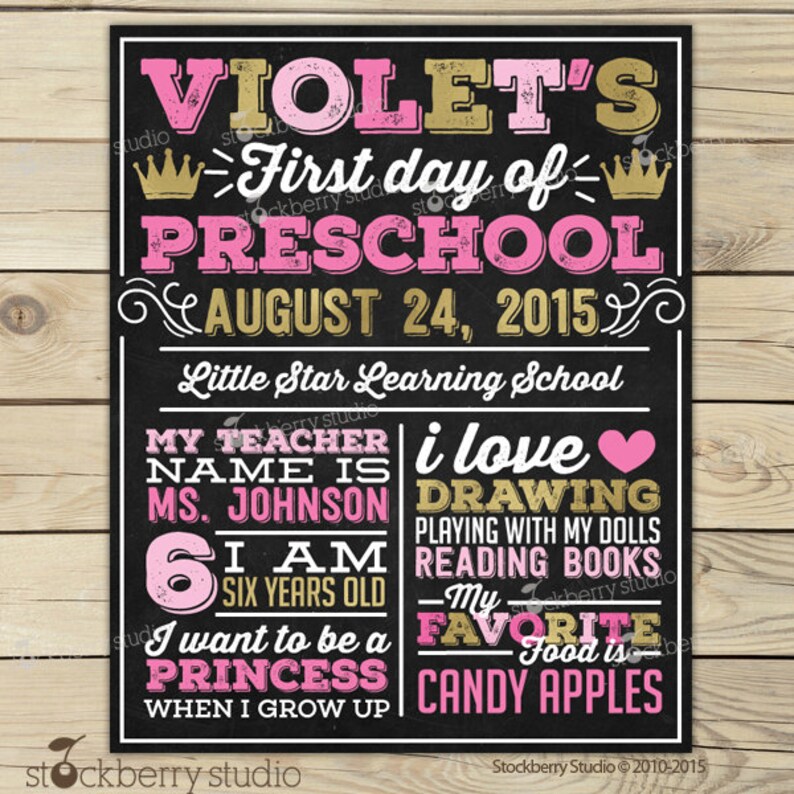 May include: A chalkboard-style sign with pink and gold text. It reads "Violet's First day of Preschool, August 24, 2015." Additional text includes "My teacher is Ms. Johnson, I am six years old, I want to be a princess, and my favorite food is candy apples."