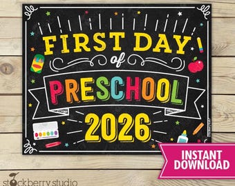May include: A rectangular black chalkboard sign with white, yellow, red, blue, and green text reading FIRST DAY of PRESCHOOL 2026. The design features colorful illustrations of a crayon box, an apple, a paint set, and various school supplies.
