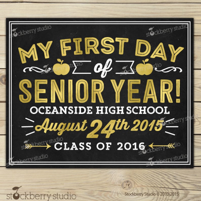 Op de afbeelding: Een zwart schoolbordbord met gouden en witte tekst. Er staat "MY FIRST DAY of SENIOR YEAR!" met de datum 24 augustus 2015 en "CLASS OF 2016". Het bord is wit omlijst.