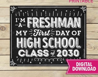 Puede incluir: Un letrero rectangular de pizarra negra con texto blanco que dice I'M A FRESHMAN MY FIRST DAY OF HIGH SCHOOL CLASS of 2030. El diseño presenta líneas, estrellas y remolinos decorativos en blanco, con el texto stockberry studio PRINTABLE arriba.