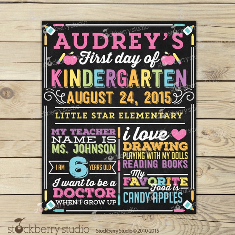 May include: A chalkboard-style sign with colorful text announcing "Audrey's First day of Kindergarten" on August 24, 2015. The sign includes details about the teacher, favorite activities, age, and future aspirations.