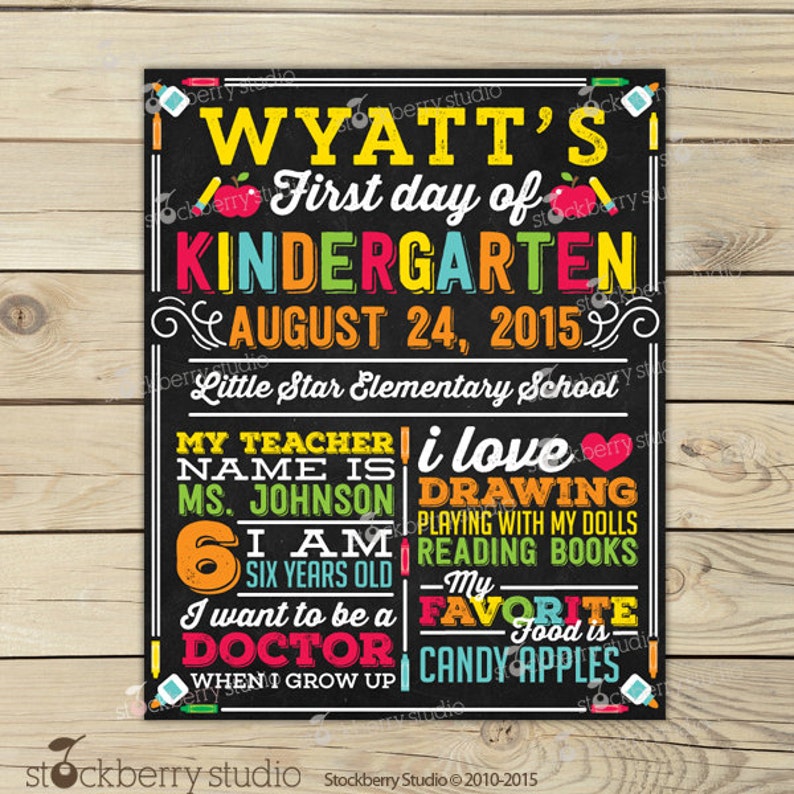 May include: A chalkboard-style sign with colorful text announcing "Wyatt's First day of Kindergarten, August 24, 2015." It includes details about the child's teacher, age, interests, and aspirations. The sign is decorated with school-themed illustrations.
