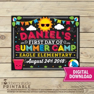 May include: A colourful chalkboard-style sign announcing "DANIEL'S FIRST DAY OF SUMMER CAMP". The sign features a smiling sun, beach balls, and the date August 24th, 2018. The words "EAGLE ELEMENTARY" are also included.