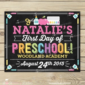 May include: A black chalkboard sign with the text "NATALIE'S First Day of PRESCHOOL!" in various colours. The sign includes school-themed illustrations and the date August 24th, 2015. The sign is framed with white lines and colourful accents.