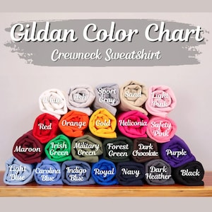 Puede incluir: Una carta de colores para sudaderas Gildan. La imagen muestra una variedad de sudaderas enrolladas en varios colores, incluyendo blanco, rojo, naranja, dorado y morado. El texto "Gildan Color Chart Crewneck Sweatshirt" est&aacute; en la parte superior.