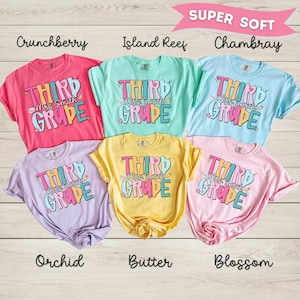 May include: Six short-sleeved t-shirts in various colors including pink, teal, light blue, lavender, yellow, and light pink. Each shirt features the text "THIRD GRADE" and "Mrs. Smith" in a colorful, retro-style font with small star and heart accents.