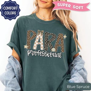 May include: A dark teal t-shirt featuring the text PARA in large letters with leopard print, checkered, and polka dot patterns, and the word professional in white script below. The design includes a small bow, a star, and a smiley face icon.
