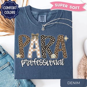 May include: A denim blue t-shirt featuring the word PARA in large letters with leopard print and checkered patterns, topped with a small bow graphic. Below, the word professional is written in white script. A smiley face and stars are included.