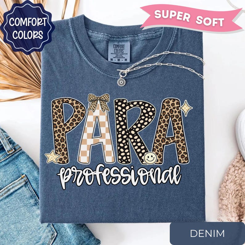 May include: A denim blue t-shirt featuring the word PARA in large letters with leopard print and checkered patterns, topped with a small bow graphic. Below, the word professional is written in white script. A smiley face and stars are included.